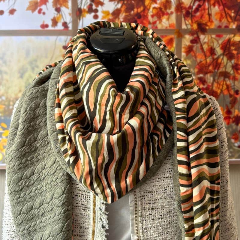 Chèche femme réversible kaki et saumon, foulard triangle porté sur mannequin, tissu rayé multicolore et doublure sweat matelassée, fond décor automnal.