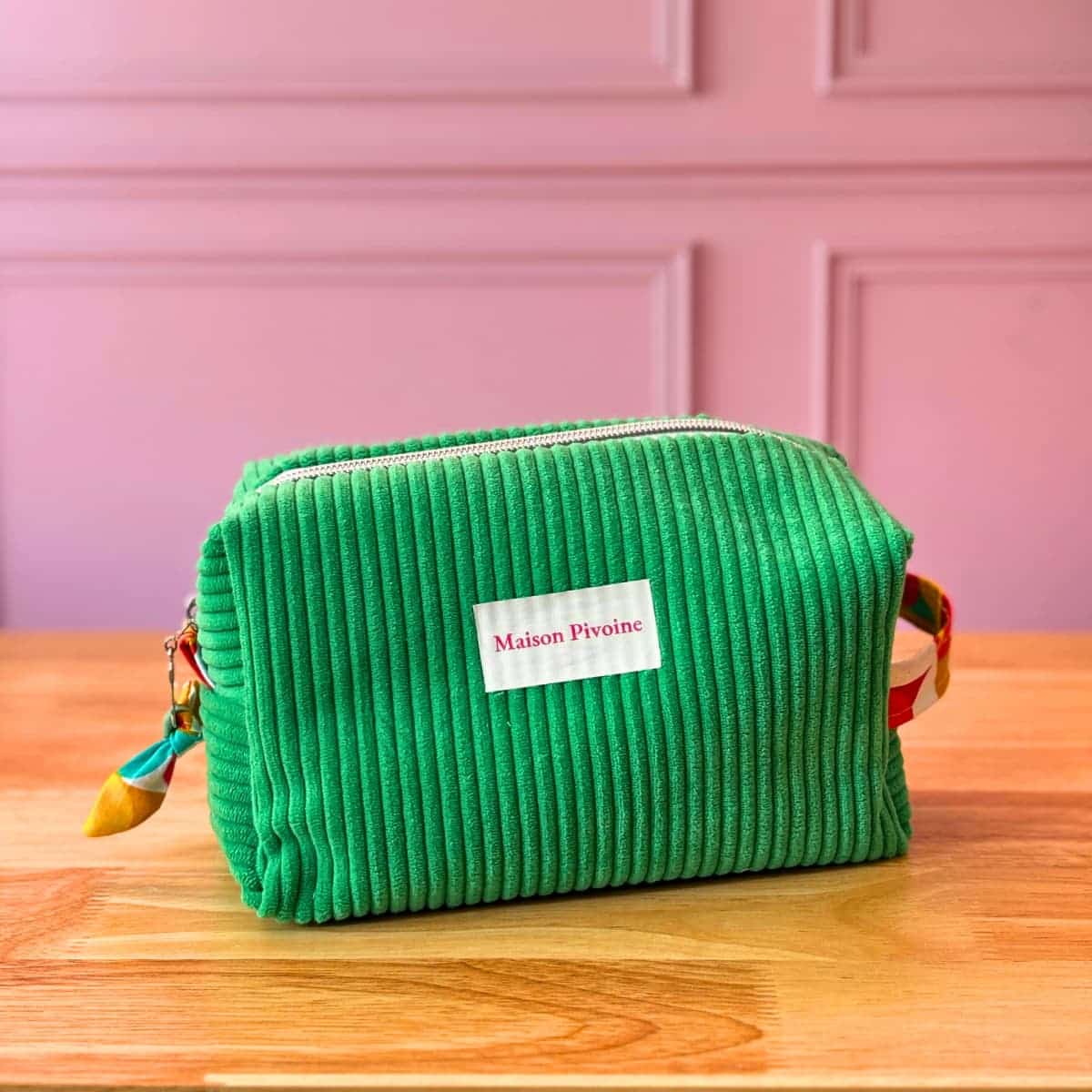 Vue de face d'une trousse de toilette en velours côtelé vert, création textile artisanale bretonne par Maison Pivoine.