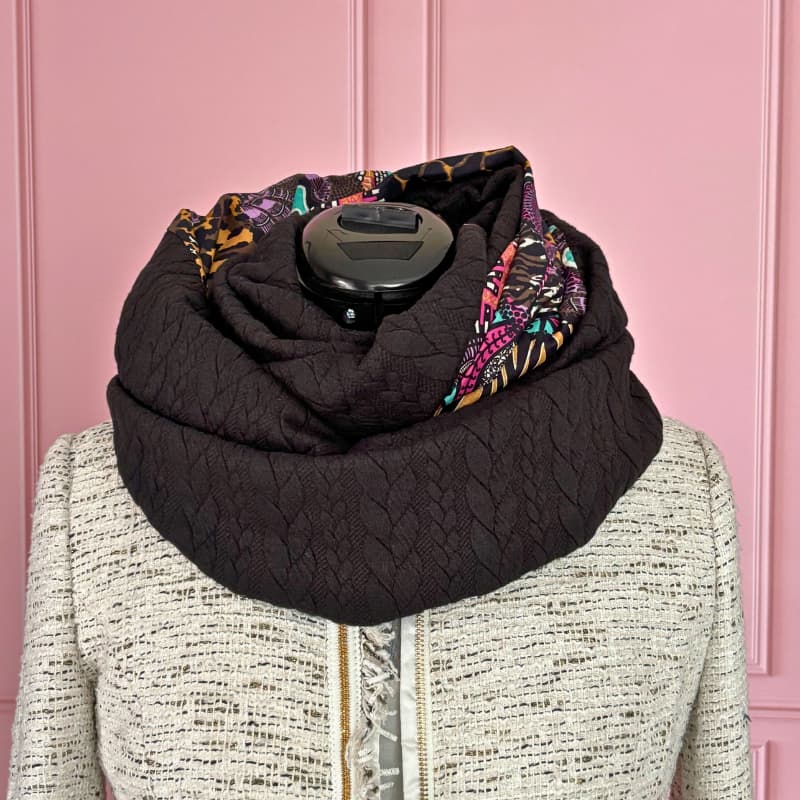 Écharpe tube réversible : un côté en tissu noir texturé ultra doux, l’autre côté en coton imprimé tropical aux tons verts et roses. Elle se porte en un ou deux tours pour jouer avec les deux faces et changer de look en un clin d’œil. Parfaite pour celles qui aiment les détails colorés tout en gardant une base noire élégante.