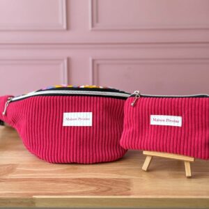 Parure Maison Pivoine fuchsia : sac banane XXL et pochette assortie présentés sur un support en bois.