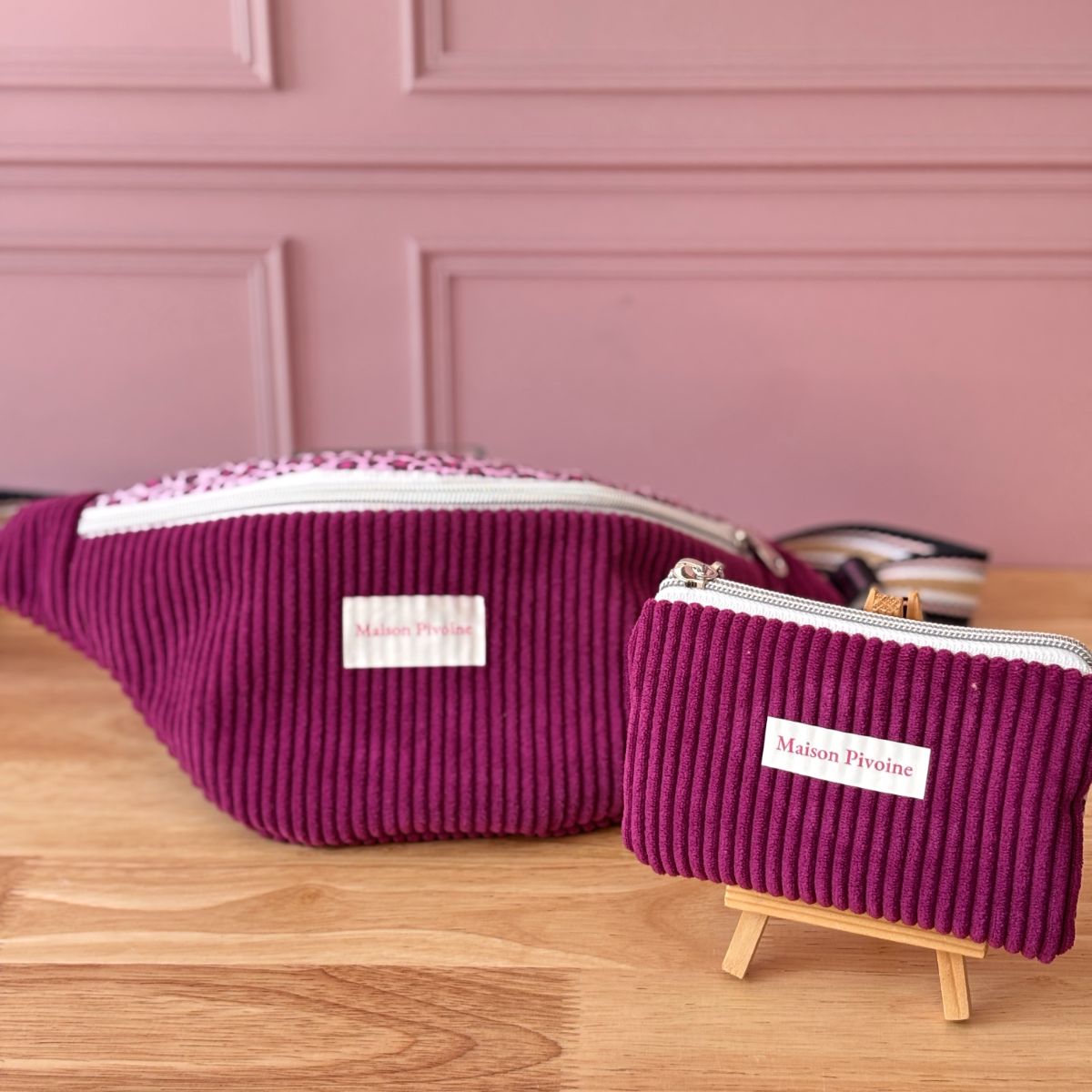 Duo Maison Pivoine coloris violet : sac banane velours et trousse zippée assortie sur présentoir bois.