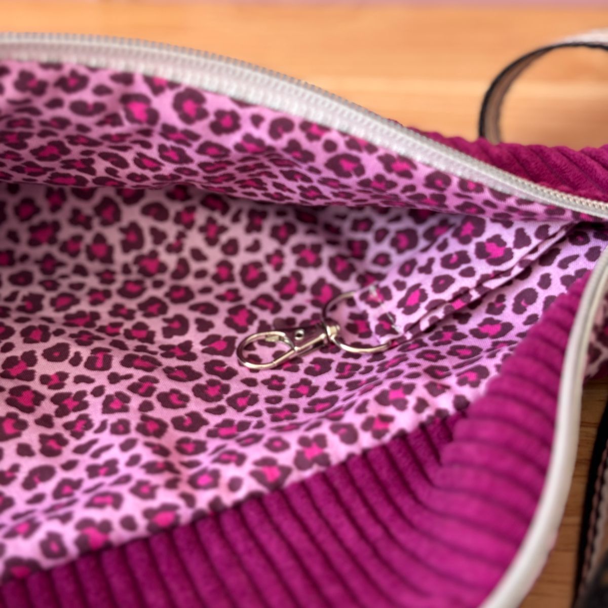 Intérieur du sac banane violet ouvert : doublure coton motifs léopard rose et cordon mousqueton porte-clé