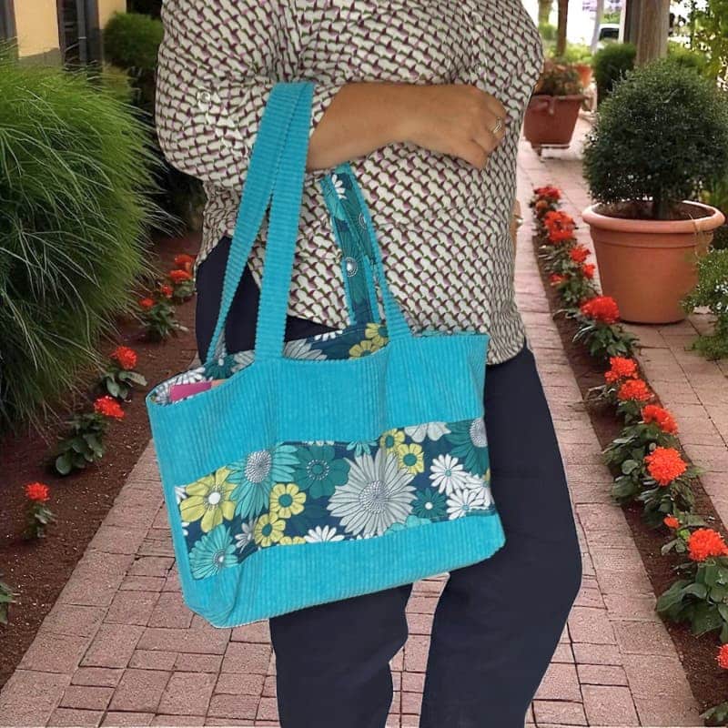 Sac cabas artisanal en velours côtelé turquoise avec tissu fleuri vert et blanc, porté sur le bras– création Maison Pivoine.