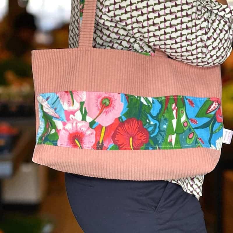 Sac cabas artisanal Maison Pivoine en velours côtelé rose avec bande de tissu fleuri multicolore, porté à l’épaule.