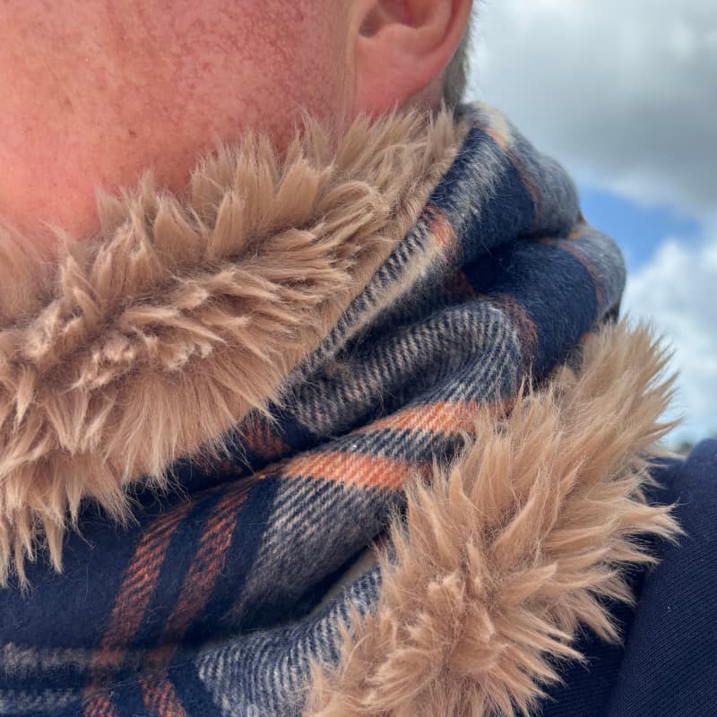 Gros plan sur un snood homme en laine à carreaux bleu marine et caramel doublé de fausse fourrure camel, accessoire hivernal Maison Pivoine.