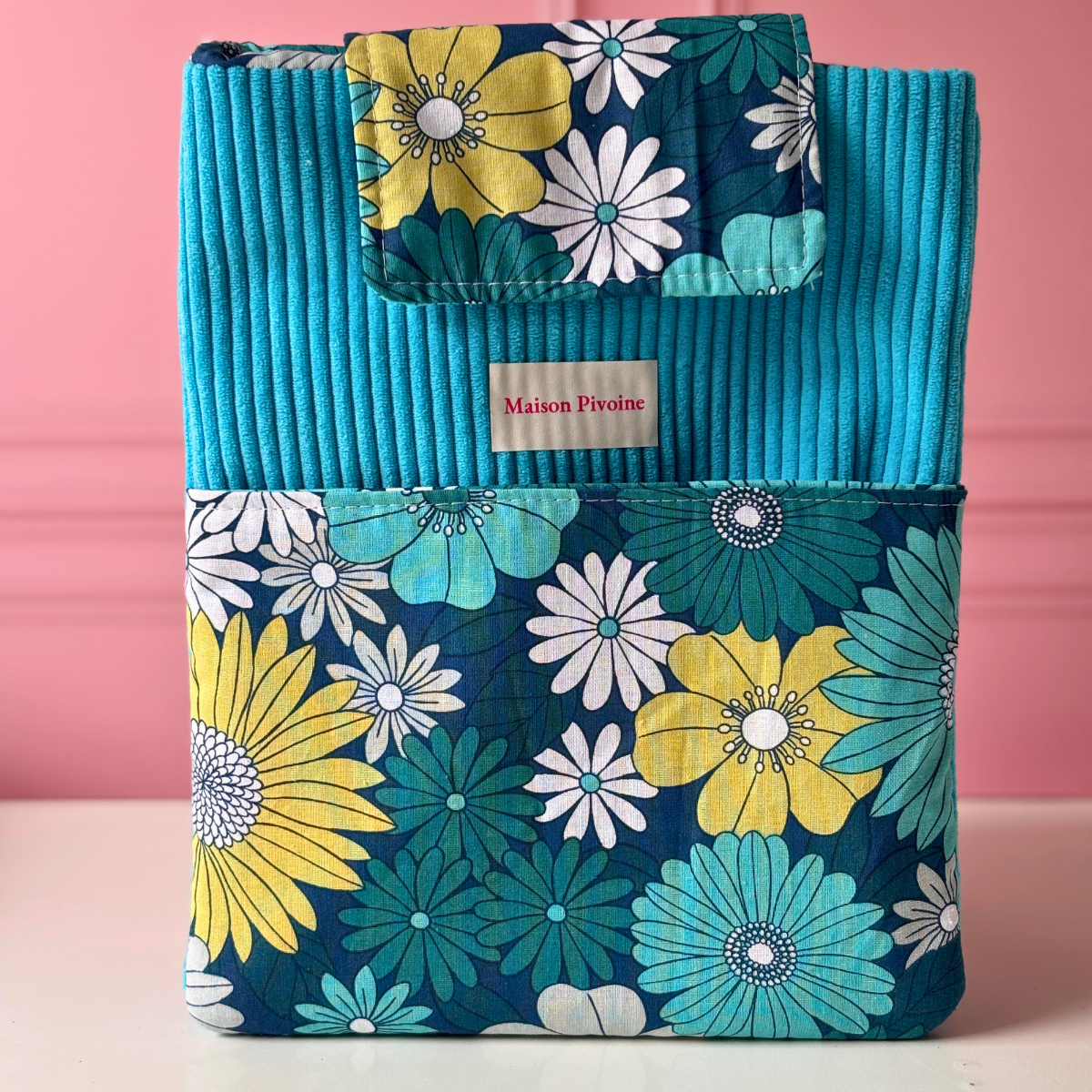 Pochette à livre format roman ouverte montrant l'intérieur d'un livre en cours de lecture, réalisée en velours côtelé bleu turquoise et tissu fleuri aux teintes bleues, vertes et jaunes.